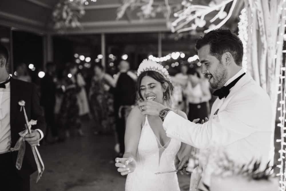 black and white photo of groom feeding bride cake