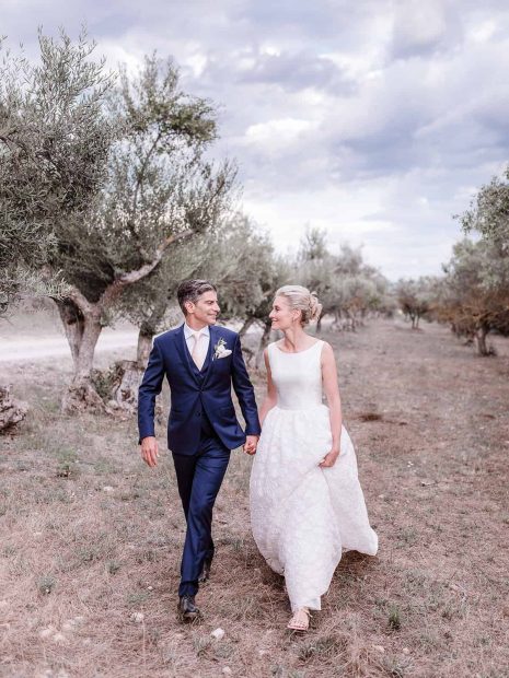 newly weds walk through olive grove