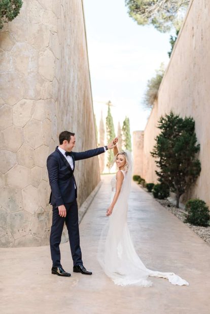 bride twirls while holding the grooms hand outside at cap rocat wedding venue in mallorca