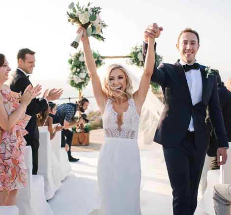 just married couple celebrate coming back up the aisle with arms in the air at cap rocat wedding venue in mallorca spain