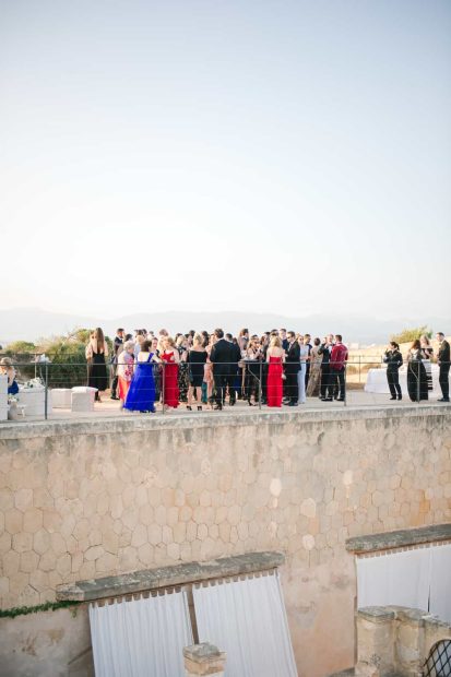 wedding guests mingle on balcony at cap rocat wedding venue in mallorca spain