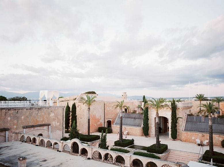 vast terracotta stone courtyard with tall palms at cap rocat spanish wedding venue
