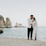 groom and bride stand on the shoreline
