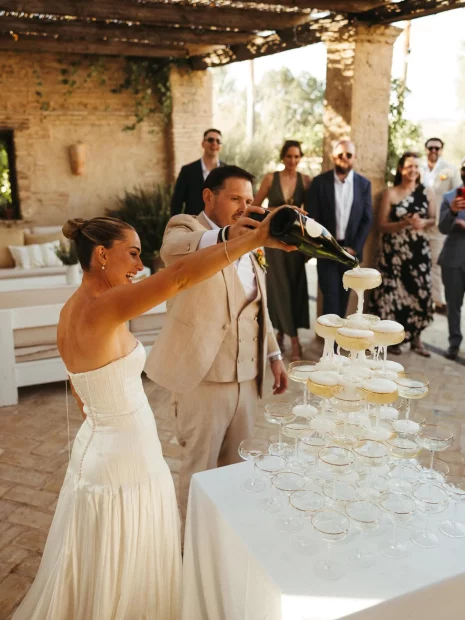 Image of couple pouring champagne into champagne tower at wedding venue Casa La Siesta