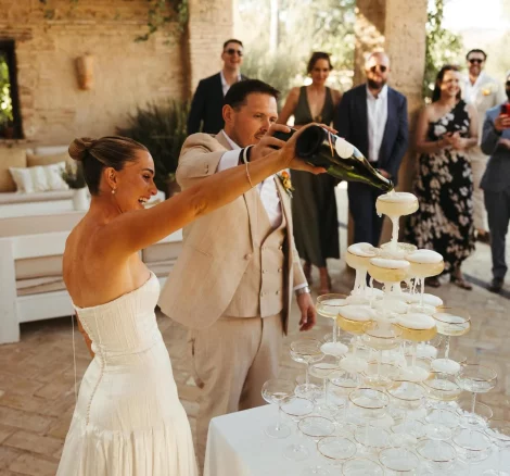 Image of couple pouring champagne into champagne tower at wedding venue Casa La Siesta
