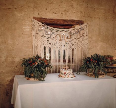 simple naked wedding cake with a macrame back drop on a white tablecloth spanish wedding venue casa la siesta