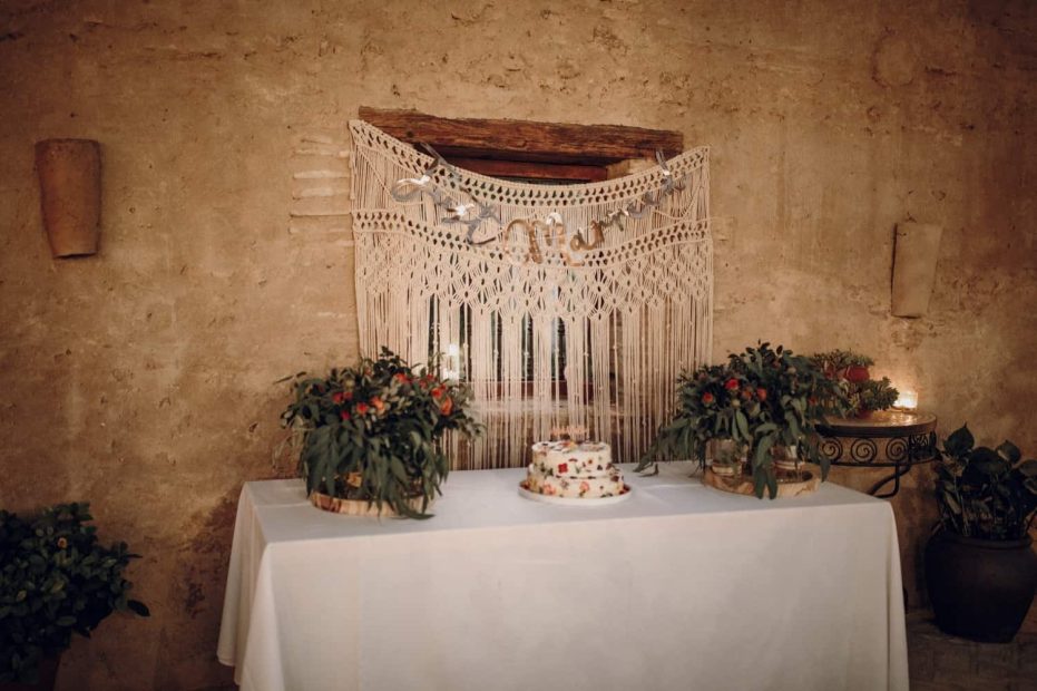 simple naked wedding cake with a macrame back drop on a white tablecloth spanish wedding venue casa la siesta