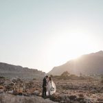 bride and groom pose on rocky landscape