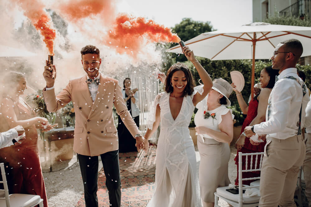 jess and adam holding smoke bombs after wedding