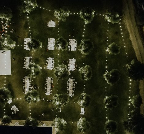 An aerial view of wedding breakfast tables under a fairy light draped lawn early evening at one of the best destination wedding venues in Italy, Masseria Don Luigi