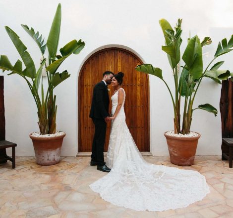 bride and groom stood hand in hand facing each other outside a wooden arched doorway at hacienda na Xamena unique wedding venue in ibiza