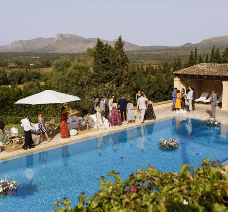 wedding guests stood around the rectangular outdoor pool at mallorca wedding venue son doblons in spain