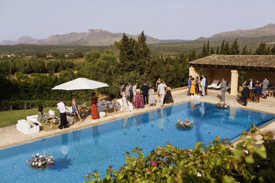 wedding guests stood around the rectangular outdoor pool at mallorca wedding venue son doblons in spain