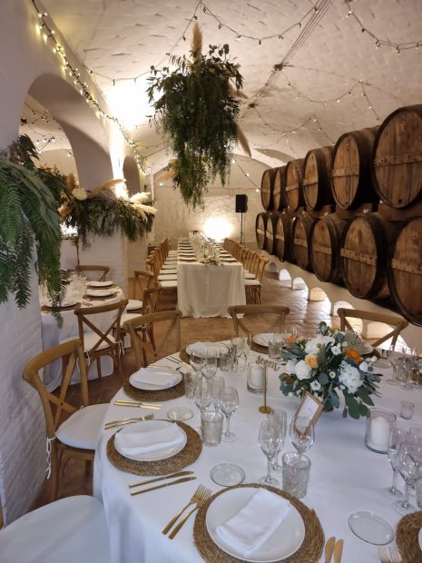 underground wine cellar with white arched ceilings decorated with pampas grass for a wedding reception at villa Catalina in spain