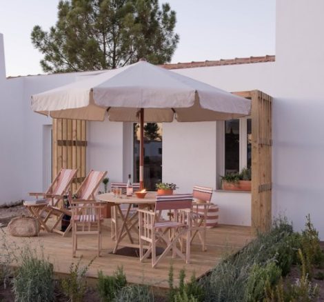 outdoor decking area with wooden table and chairs at accommodation at craveiral farmhouse in portugal