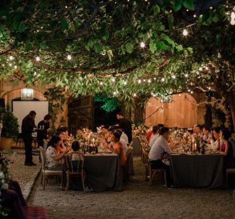 Al fresco wedding dinner at sundown with fairy lights strung over the courtyard