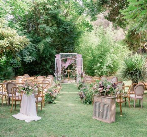 Wedding Ceremony on the grass with an eclectic mix of wooden chairs at rustic spanish wedding venue Villa Catalina