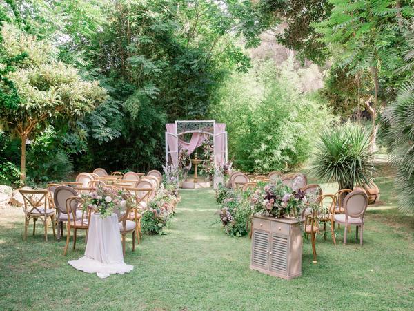 Wedding Ceremony on the grass with an eclectic mix of wooden chairs at rustic spanish wedding venue Villa Catalina