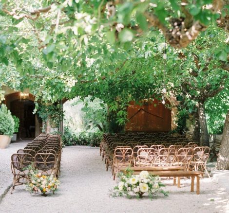 Wooden ceremony chairs under a copy of trees at spanish wedding villa