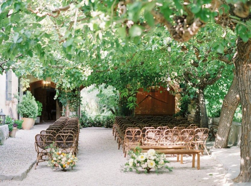 Wooden ceremony chairs under a copy of trees at spanish wedding villa