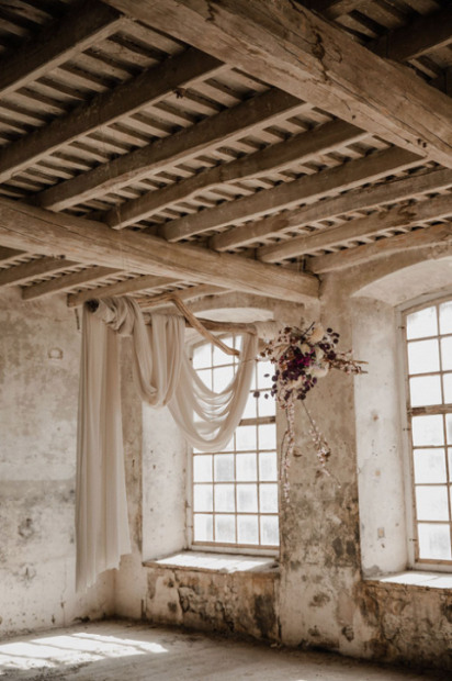 Driftwood hanging with draped material and purple floral arrangement at spanish wedding venue colonia rusinol