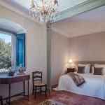 double bedroom with wooden table and chairs and view out the wooden shutters at spanish wedding venue Masia Victoria