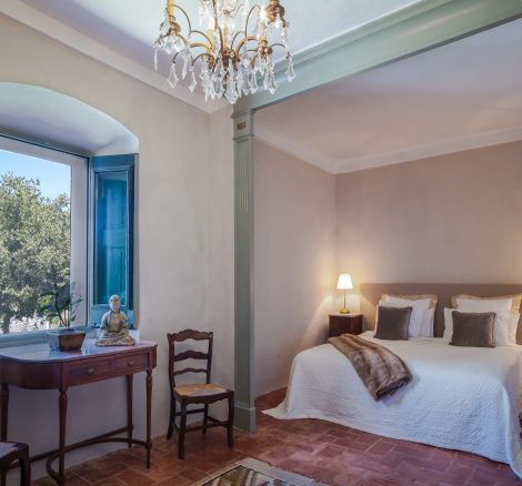 double bedroom with wooden table and chairs and view out the wooden shutters at spanish wedding venue Masia Victoria