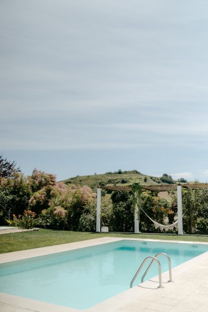 the pool area and lawn with a macrame hammock at wedding venue casa sacoto in portugal