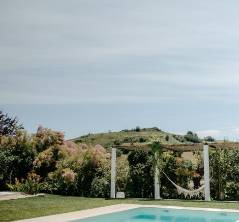 the pool area and lawn with a macrame hammock at wedding venue casa sacoto in portugal