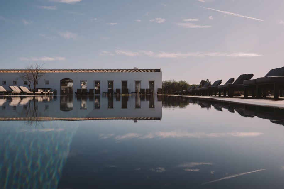 exterior shot across the pool up towards the white walls of craveiral farmhouse a unique wedding venue in portugal