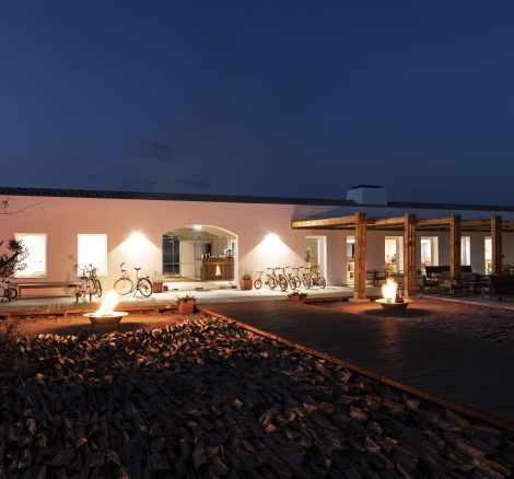 the exterior of craveiral farmhouse in portugal at night with lights shining from inside the property