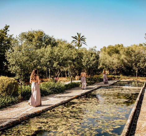 bridesmaids walking down the aisle alongside the outdoor cascading pond at Son Doblons wedding venue in mallorca spain