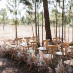 wooden wedding chairs lined with dried pampas at outdoor wedding ceremony in portugal at craveiral farmhouse