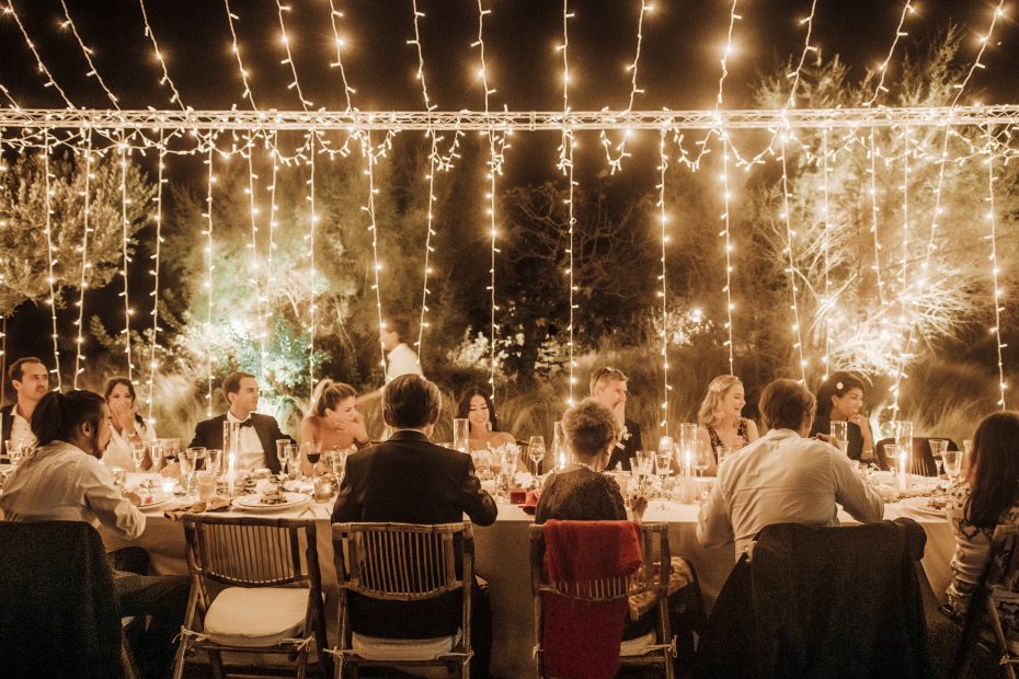 fairy lights hung overhead of the dining tables where guests are seated at ca na xica wedding venue in ibiza