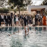 guests crowd around the outdoor pool at wedding venue ca na xica in ibiza to watch synchronised swimmers