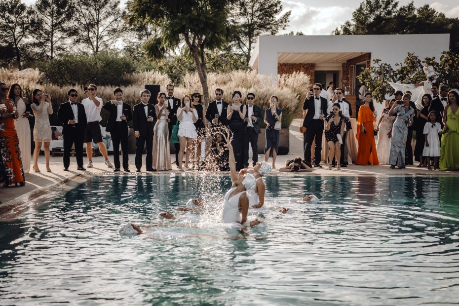 guests crowd around the outdoor pool at wedding venue ca na xica in ibiza to watch synchronised swimmers