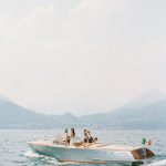 bride and her bridesmaids on a traditional wooden Italian boat from villa cipressi in Italy