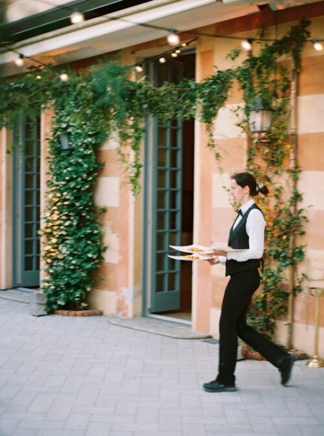Waiter serving wedding meal outside Italian wedding venue Villa Cipressi