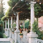 wedding guests sat underneath a wooden pergola at Italian wedding venue Villa Cipressi on Lake Como