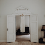 bridal gown hung from the door frame of polish wedding venue the palace osowa sien