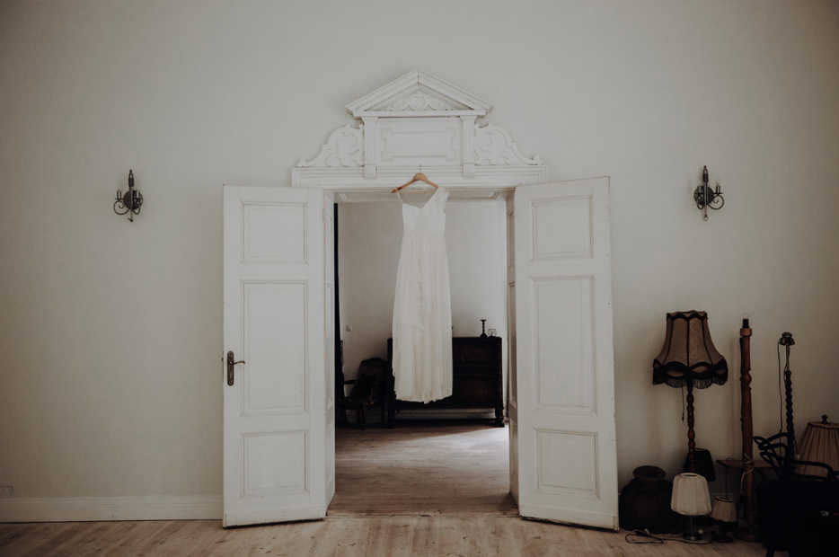 bridal gown hung from the door frame of polish wedding venue the palace osowa sien