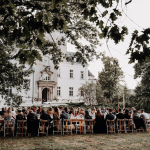 wedding guests sat down at wooden tables for al fresco wedding reception of polish wedding venue the palace osowa sien