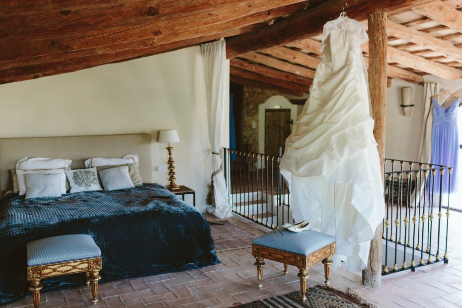 white wedding dress hung in the bedroom at spanish wedding venue Masia Victoria