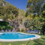 outdoor pool and loungers surrounded by trees at villa Catalina in spain
