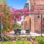 outdoor seating area with climbing pink flowers overhead at son doblons spanish wedding venue in mallorca