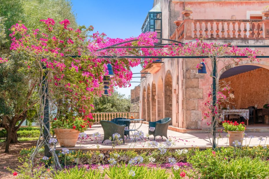 outdoor seating area with climbing pink flowers overhead at son doblons spanish wedding venue in mallorca