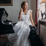 bride sat with black dog whilst sitting at a grand piano at The Palace Osowa Sien in Poland