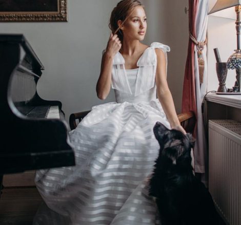 bride sat with black dog whilst sitting at a grand piano at The Palace Osowa Sien in Poland