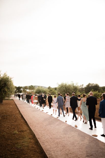 wedding guests walking towards the ceremony set up outside on the grounds of ca na xica in Ibiza a beautiful wedding venue in the Balearic Islands
