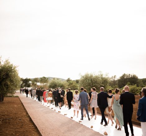 wedding guests walking towards the ceremony set up outside on the grounds of ca na xica in Ibiza a beautiful wedding venue in the Balearic Islands